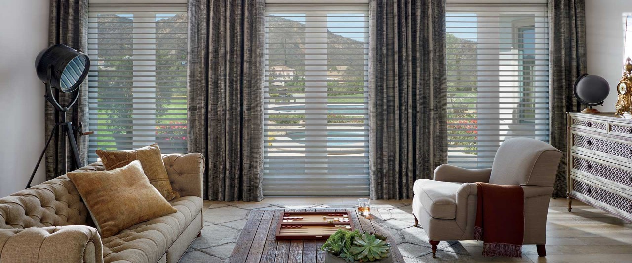 Moody living room with tufted couch and large windows.